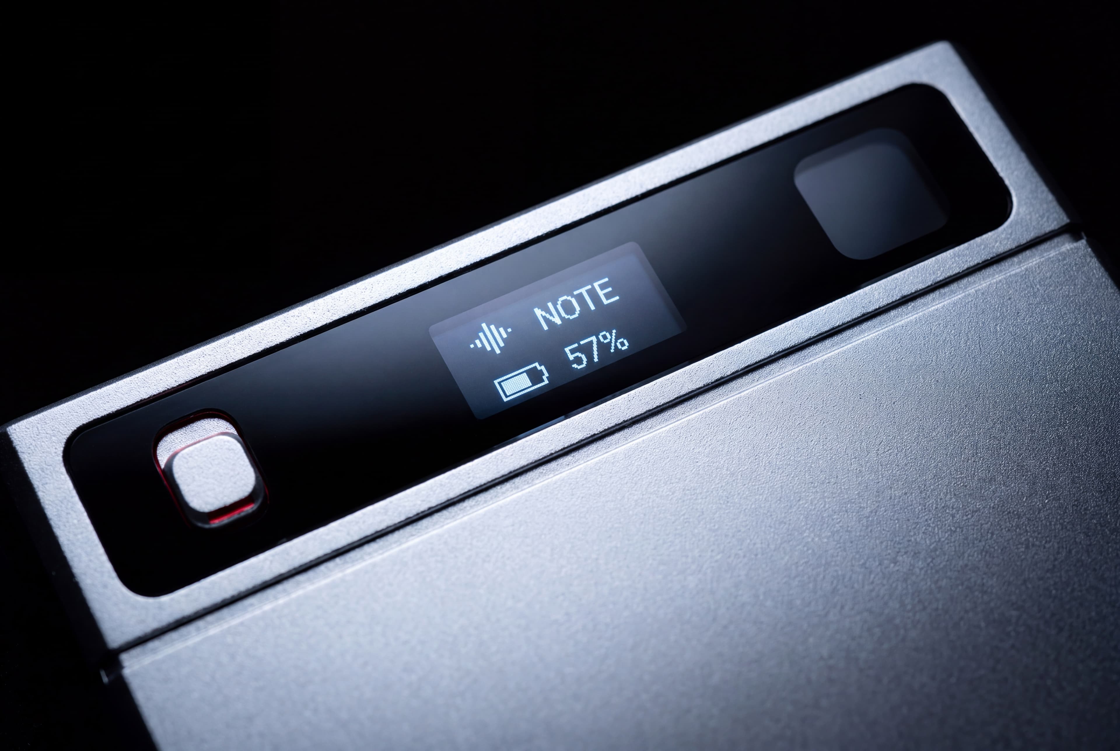 Macro of the glass band, lit — a live audio meter and the battery level glowing through the black glass.